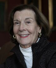 Carolyn Turchon with medium length brown hair wearing a white turtleneck under a black jacket
