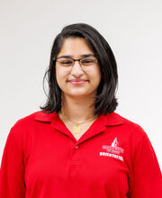 Alezza Ghani smiling with medium length dark brown hair and wearing black rim glasses and a red BSU Orientation Leader polo