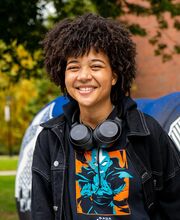 a woman smiles at camera wearing headphones around her neck