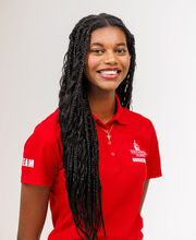Cintia Mascarenhas smiling with long braided black hair and wearing a red BSU Orientation Leader polo