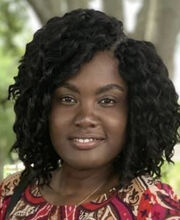 Tatiana Francois smiling with medium length wavy black hair and wearing a red black and tan top