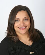 Ann Ulett smiling with long dark brown hair and wearing a long sleeve black top