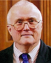 headshot photo of Dr. Charles Cox wearing dark blazer, striped button down shirt and blue tie