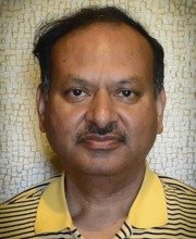 Proffesor Subhendu Roy with short dark hair and mustache wearing a yellow and black horizontally striped polo shirt with yellow collar