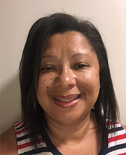 headshot photo of Maria Amado with medium length black hair wearing a red, white and blue horizontally striped sleeveless top