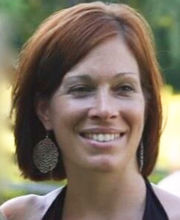 Audra Carabetta smiling with medium length reddish brown hair wearing a black halter top