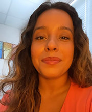 headshot photo of Kelly Lopez with long dark brown wavy hair wearing a red v-neck top