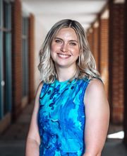 Dr. Alyssa Lankone smiling with medium length dirty blonde hair wearing a teal blue sleeveless dress