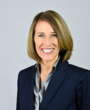 headshot photo of Elissa Pototsky smiling with dark blonde hair wearing a navy blue blazer over a grey button down blouse