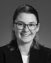 black and white headshot of Rebecca Fleming smiling and wearing glasses with her hair pulled back and large teardrop earrings