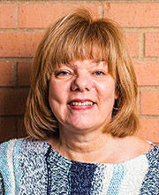 headshot photo of Christine Rowan with medium length light brown hair wearing vertically striped blue and white sweater