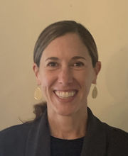 Dr. Pam Szczgiel smiling with brown hair pulled back in a low pony tail wearing long gold drop earrings and a black blazer over a black top
