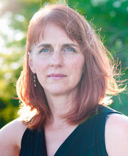 Dr. Jody Weber with medium length red/brown hair and blue eyes wearing a sleeveless black v-neck top