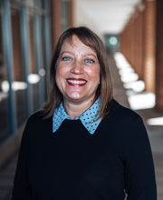 Dr. Jennifer Winters smiling with medium length brown hair and wearing a light blue polka dot collared top under a navy blue sweater