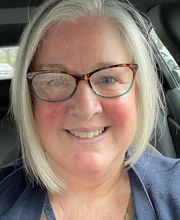 headshot photo of Dr. Catherine Womack smiling with a gray bob hairstyle wearing brown rim glasses and a blue top