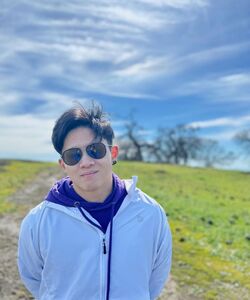 a man wearing sunglasses and a white zip-up jacket against blue sky