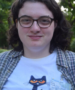 smiling individual with curly brown hair and glasses