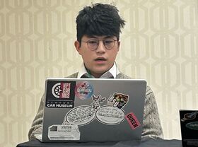 A man sits and looks at a laptop screen