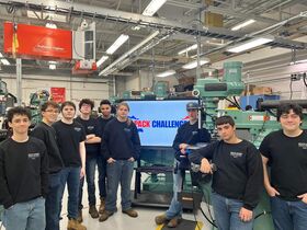 A group of students wearing black shirts smile for the camera
