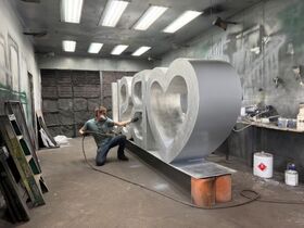 A student uses a tool to polish a Heart BSU scuplture.