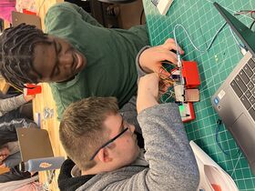 Two students programming a sensor on a work table