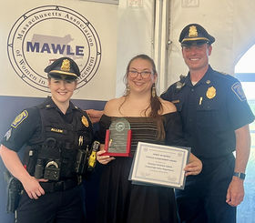 Christina LaRose holds her award while standing next to two police officers.