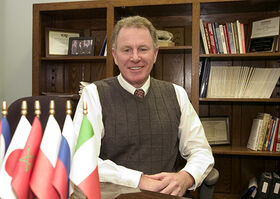 Ed Minnock sitting at a desk with flags on the desk.