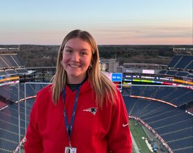 A woman smiles standing in a football stadium