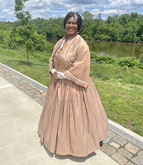 Dorrette Bogle Stephenson as a reenactor poses for a photo wearing a dress.
