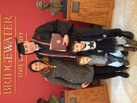 Weston Smith wearing a cap and gown with his family in front of a BSU sign.