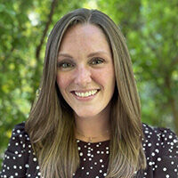 Tabitha Smith smiling with long straight light brown hair and wearing a black top with white polka dots