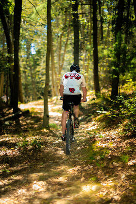 A man on a bike rides on a trail in the woods
