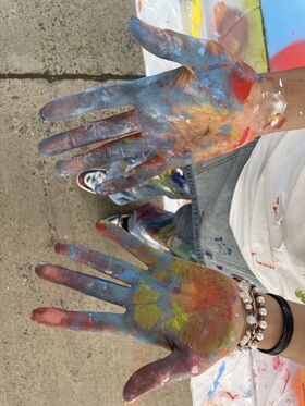 A pair of hands are held outright covered in paint