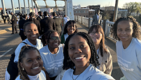 6 female students stand on the Edmund Pettus Bridge in Selma Alabama on day 1 of Alternative Break