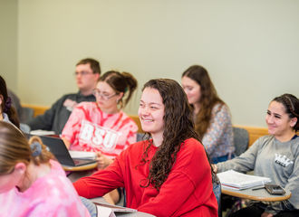 Students at their desks smiling, in a cultural diversity in special education class