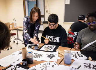 A professor guides students in a Japanese calligraphy class
