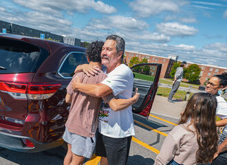 A father hugging a new BSU student in the residence hall parking lot on move-in day