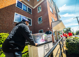 A father helps his son push a cart during move in days