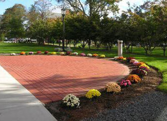 a photo of a half circle of bricks next to Boyden Hall surrounded by flowers