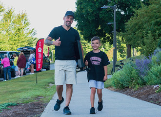 A parent gives a thumbs up while walking with his young son at move in day