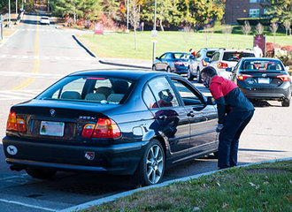 A car pulled over to the side of the road, a man leans over to the car window