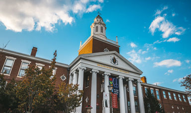 The front of Boyden Hall with leaves turning color in the trees and the Peace sign hung over the stairs