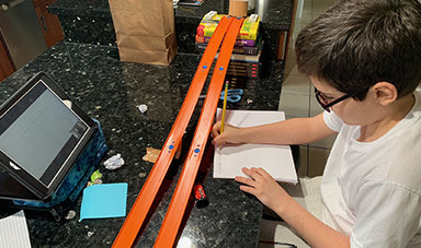 A youngster uses Hot Wheels cars and a track to learn about science from BSU students.