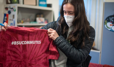 Student holding t shirt with #BSUCommutes written on it