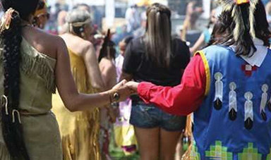 People holding hands at a powwow.
