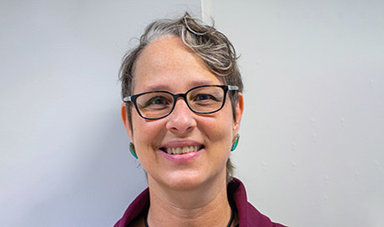 Judith Willison poses for a photo in front of a white wall.