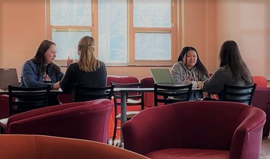 Four women sit in chairs talking to each other