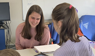 Adlai Greene works with a female student at a table.