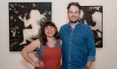 A man and woman stand next to each other smiling