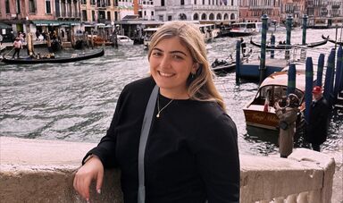 A woman stands and smiles at the camera